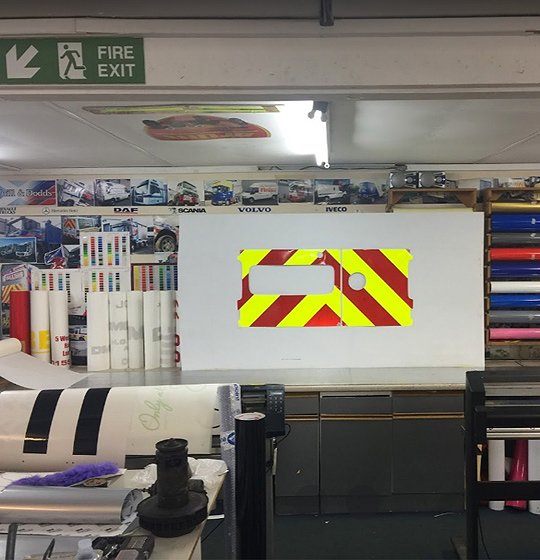 The A. Gray & Sons graphics studio with vinyl rolls and a chevron panel in production